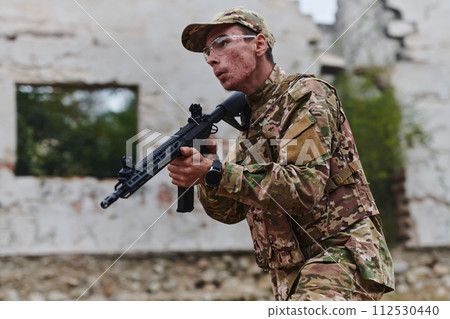 An elite soldier, camouflaged and stealthily navigating through dangerous woodland terrain, executes a covert mission in a secluded forest area 112530440