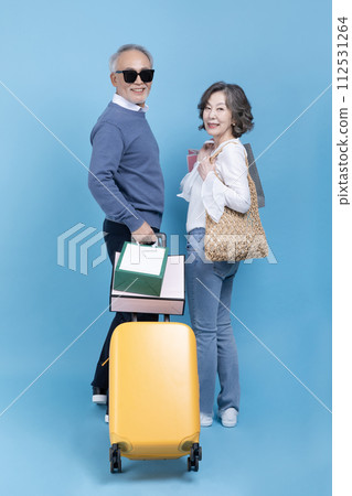 Senior carrying a suitcase and a shopping bag 112531264