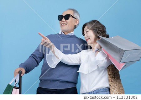 Senior carrying a suitcase and a shopping bag Senior carrying a suitcase and a shopping bag 112531302