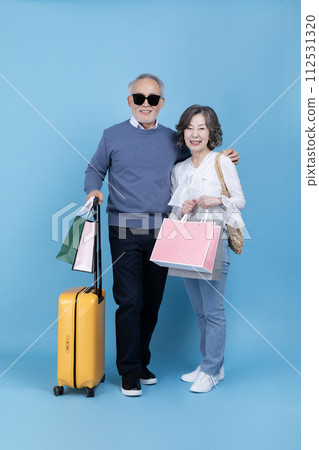 Senior carrying a suitcase and a shopping bag 112531320