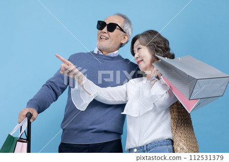 Senior carrying a suitcase and a shopping bag Senior carrying a suitcase and a shopping bag 112531379