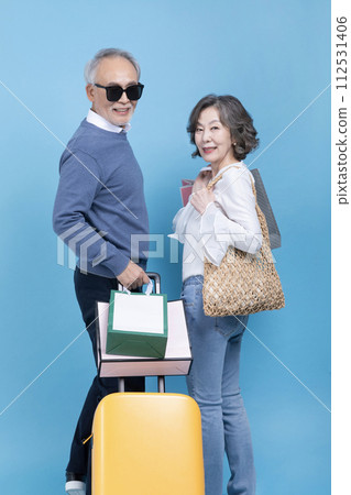 Senior carrying a suitcase and a shopping bag Senior carrying a suitcase and a shopping bag 112531406
