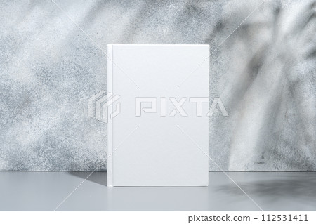 White blank book with hard cover on gray background with shadows White blank book with hard cover on gray background with shadows 112531411