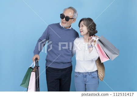 Senior carrying a suitcase and a shopping bag 112531417