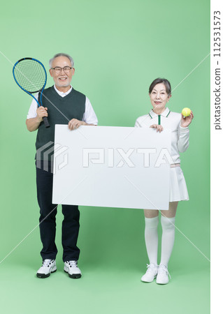 A senior holding a tennis racket, a tennis ball and blank paper 112531573