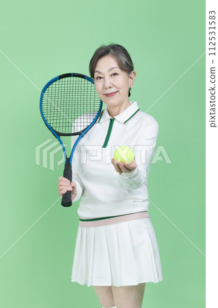 A senior woman holding a tennis racket and a tennis ball 112531583