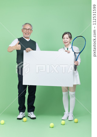 A senior holding a tennis racket, a tennis ball and blank paper 112531599