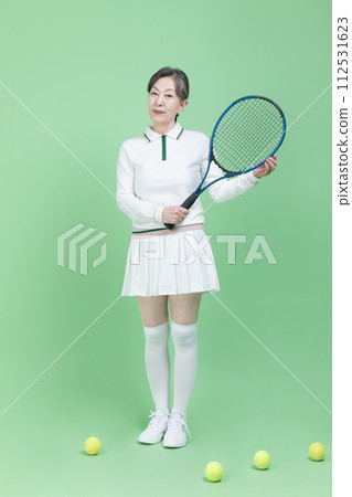 A senior woman holding a tennis racket and a tennis ball 112531623