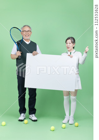 A senior holding a tennis racket, a tennis ball and blank paper 112531628