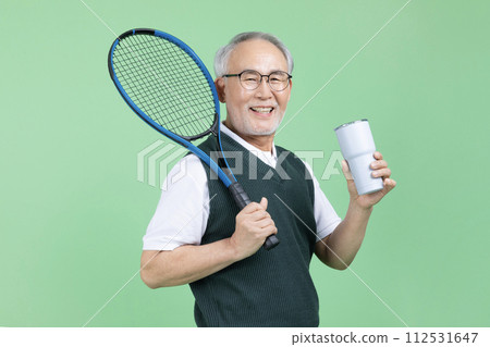 A senior male holding a tennis racket and a water bottle 112531647