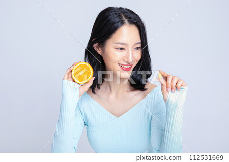 A woman holding a pill and an orange 112531669