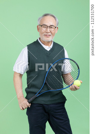 A senior male holding a tennis racket and a tennis ball A senior male holding a tennis racket and a tennis ball 112531700