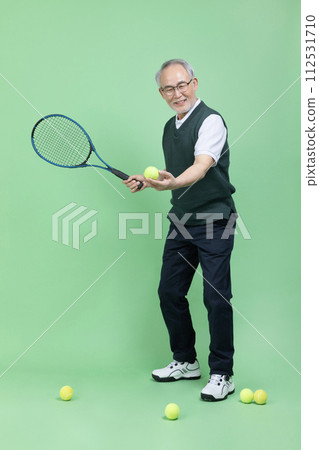 A senior male holding a tennis racket and a tennis ball 112531710