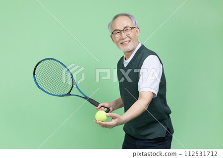 A senior male holding a tennis racket and a tennis ball 112531712
