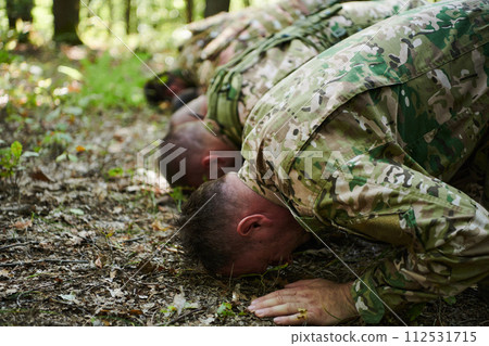 A dedicated group of soldiers engages in Islamic prayer amidst the challenging and perilous conditions of a military operation in dense forested areas 112531715