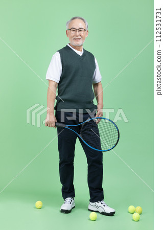 A senior male holding a tennis racket and a tennis ball A senior male holding a tennis racket and a tennis ball 112531731