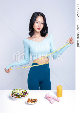 A woman in a tracksuit standing in front of a salad nut sublingual tape measure pillbox A woman in a tracksuit standing in front of a salad nut sublingual tape measure pillbox 112531747