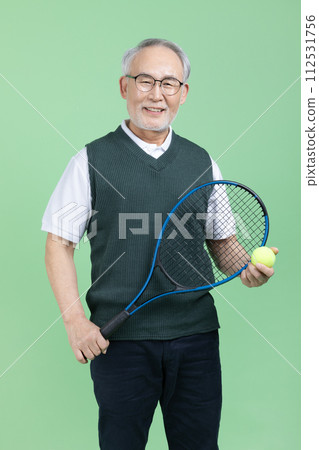 A senior male holding a tennis racket and a tennis ball A senior male holding a tennis racket and a tennis ball 112531756