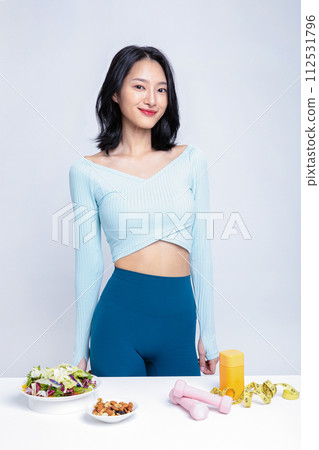 A woman in a tracksuit standing in front of a salad nut sublingual tape measure pillbox 112531796