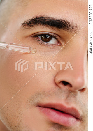 Handsome man applying skincare serum at camera close up Handsome man applying skincare serum at camera close up 112531993