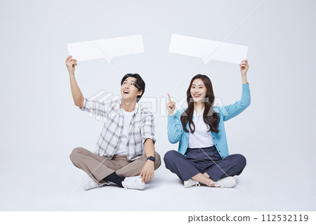 A man and a woman sitting with a cross legged empty message paper 112532119