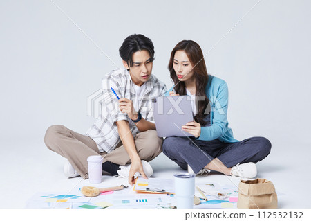 A man and a woman sitting on two legs and holding a tablet and talking A man and a woman sitting on two legs and holding a tablet and talking 112532132