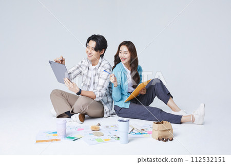 A man and a woman sitting on two legs and holding a tablet and talking 112532151