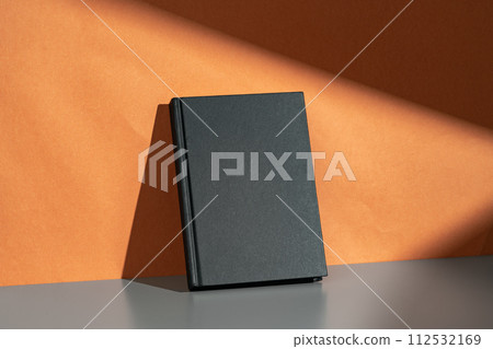 Black notepad mock up against terracotta wall 112532169