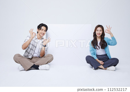A man and a woman sitting next to an empty message sheet with two legs crossed 112532217