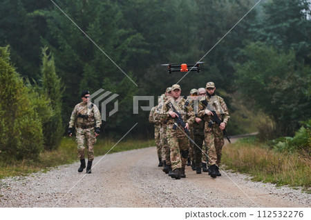 An elite military unit, led by a major, confidently parades through dense forest, showcasing precision, discipline, and readiness for high-risk operations An elite military unit, led by a major, confidently parades through dense forest, showcasing precision, discipline, and readiness for high-risk operations 112532276