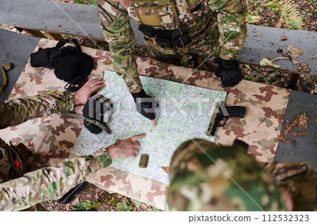 A highly trained military unit strategizes and organizes a tactical mission while studying a military map during a briefing session 112532323