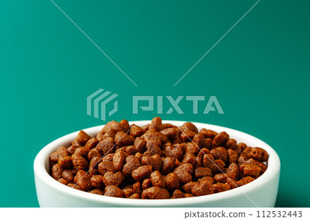 Bowl of dry pet food on green background 112532443