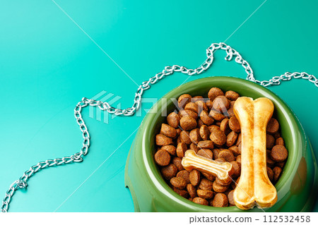 Bowl of dry pet food on green background 112532458