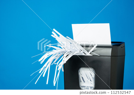 Office paper shredder on blue studio background Office paper shredder on blue studio background 112532547