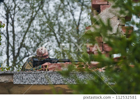 An elite soldier, camouflaged and stealthily navigating through dangerous woodland terrain, executes a covert mission in a secluded forest area An elite soldier, camouflaged and stealthily navigating through dangerous woodland terrain, executes a covert mission in a secluded forest area 112532581