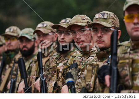 Soldier fighters standing together with guns. Group portrait of US army elite members, private military company servicemen, anti terrorist squad Soldier fighters standing together with guns. Group portrait of US army elite members, private military company servicemen, anti terrorist squad 112532651