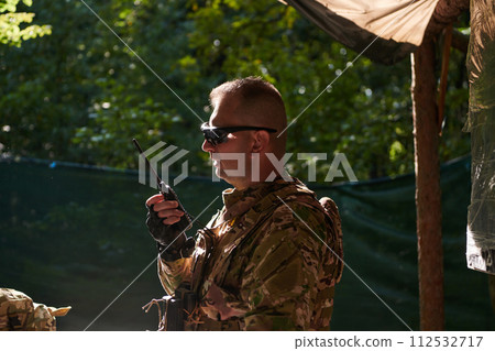 A military major employs a Motorola radio for seamless communication with his fellow soldiers during a tactical operation, showcasing professionalism and strategic coordination 112532717