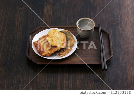 There are group pancakes, chopsticks, and glasses in the background of a wooden table There are group pancakes, chopsticks, and glasses in the background of a wooden table 112533158