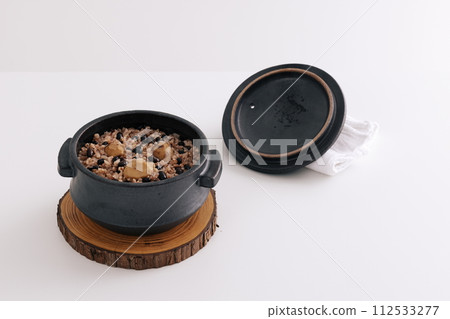 There is rice in an earthen pot and a lid is placed next to it 112533277