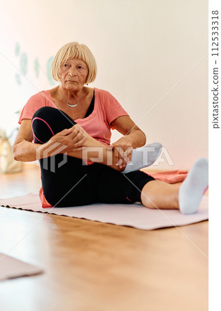 In a sunlit space, a senior woman gracefully practices rejuvenating yoga, focusing on neck, back, and leg stretches, embodying serenity and well-being In a sunlit space, a senior woman gracefully practices rejuvenating yoga, focusing on neck, back, and leg stretches, embodying serenity and well-being 112533318
