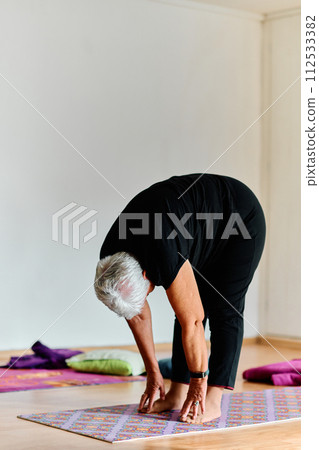 In a sunlit space, a senior woman gracefully practices rejuvenating yoga, focusing on neck, back, and leg stretches, embodying serenity and well-being In a sunlit space, a senior woman gracefully practices rejuvenating yoga, focusing on neck, back, and leg stretches, embodying serenity and well-being 112533382