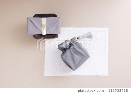 There is a bag of cash wrapped in cloth on the refreshment table and a gift cloth next to it 112533418