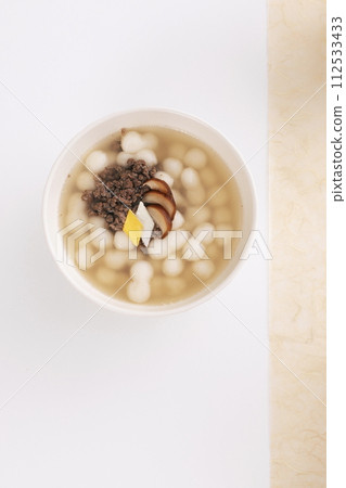 On a white table covered with Korean paper, a white bowl of gourd-shaped rice cake soup was placed 112533433