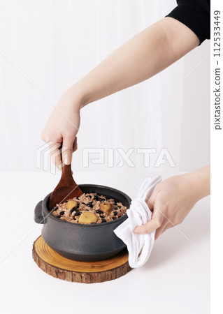 He's trying to scoop up the rice that's made in an earthen pot with a spatula 112533449