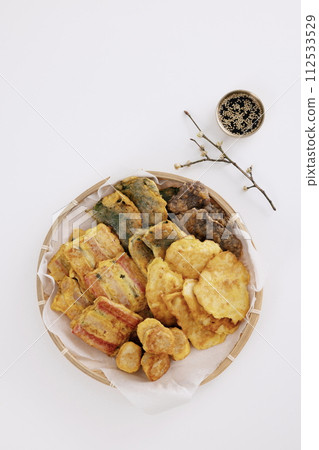 In a bamboo tray, there are lots of pancakes, and there are paper plates with branches and soy sauce In a bamboo tray, there are lots of pancakes, and there are paper plates with branches and soy sauce 112533529