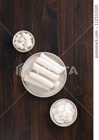With a wooden table in the background, jorangi, garae, and tteokguk are placed on a plate With a wooden table in the background, jorangi, garae, and tteokguk are placed on a plate 112533585