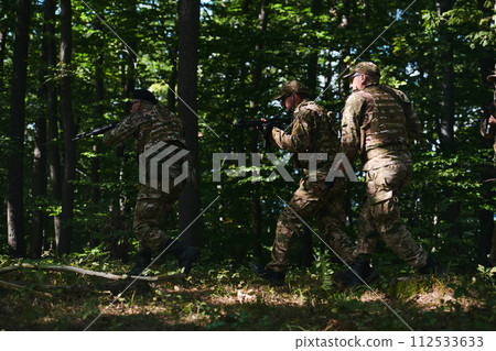 A specialized military antiterrorist unit conducts a covert operation in dense, hazardous woodland, demonstrating precision, discipline, and strategic readiness 112533633