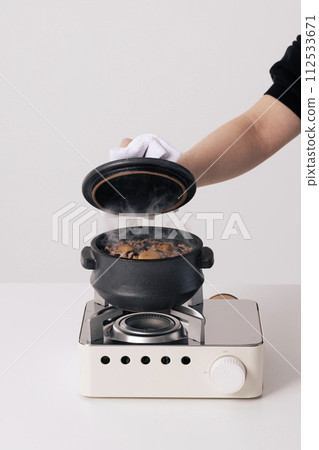 hold the lid of the pot with the hand holding the dishcloth 112533671
