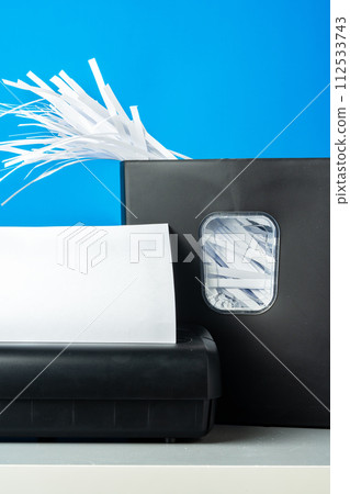 Office paper shredder on blue studio background 112533743