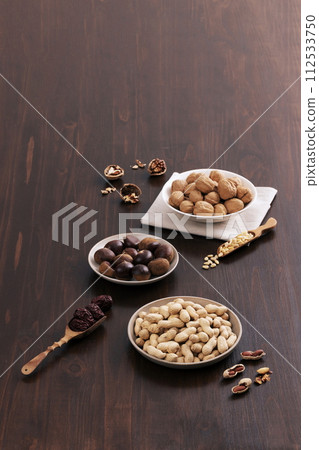 Walnuts, chestnuts, pine nuts, peanuts, and jujube are filled in plates and wooden spoon Walnuts, chestnuts, pine nuts, peanuts, and jujube are filled in plates and wooden spoon 112533750